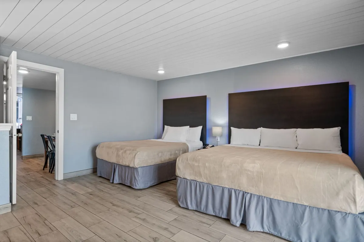 Quarto de uma suíte renovada do Celebration Suites, com duas camas e acesso à área de estar.